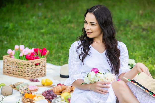 beautiful brunette woman resting in park sitting on a picnic blanket Relaxing in nature