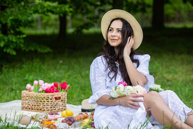 beautiful brunette woman resting in park sitting on a picnic blanket Relaxing in nature