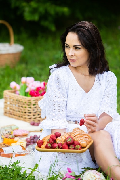 beautiful brunette woman resting in park sitting on a picnic blanket Relaxing in nature