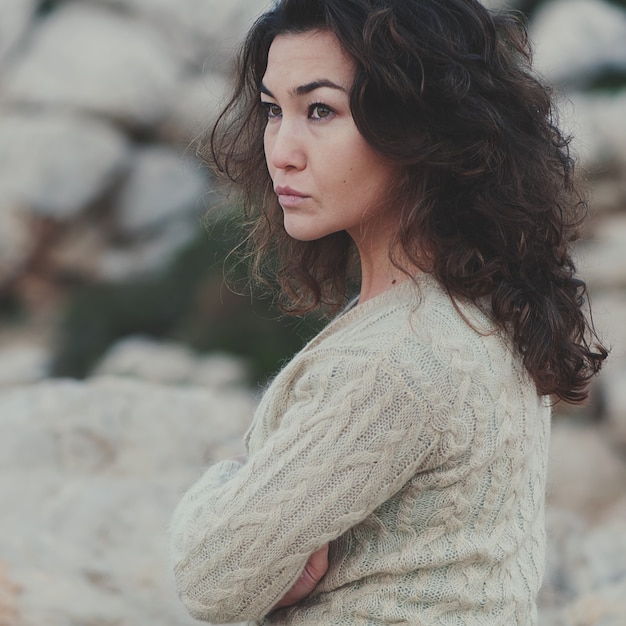 Beautiful brunette woman sitting near the rocks