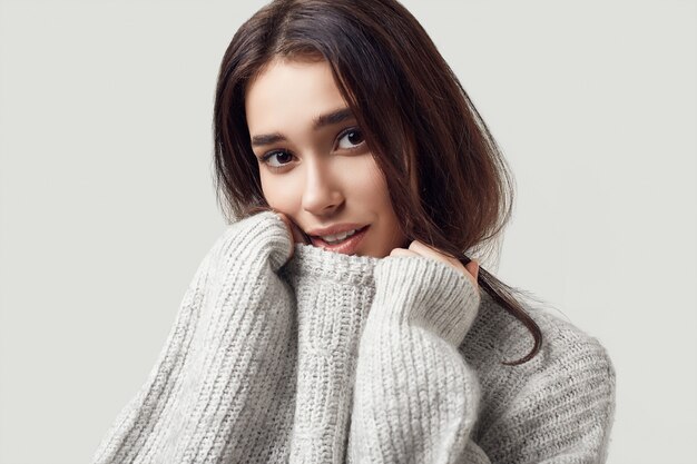 Beautiful brunette woman in sweater posing in studio