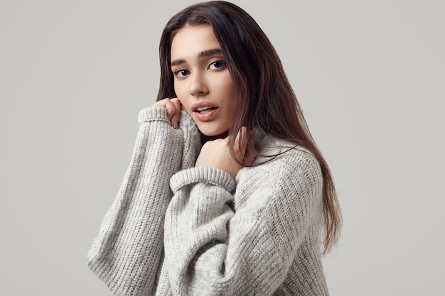 Beautiful brunette woman in sweater posing in studio