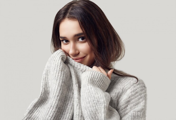 Photo スタジオでポーズをとるセーターの美しいブルネットの女性