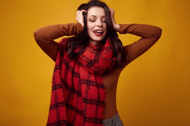 Foto bella donna bruna in maglione e cappello rosso con grande sciarpa lavorata a maglia