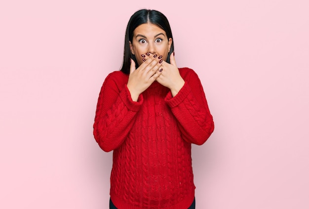 Beautiful brunette woman wearing casual sweater shocked covering mouth with hands for mistake. secret concept.