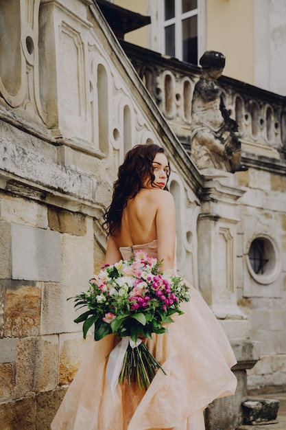 ピンクのドレスの花の花束を持つ美しいブルネットの女性