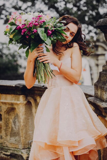 ピンクのドレスの花の花束を持つ美しいブルネットの女性