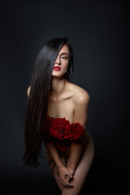 빨간 코르셋에 빨간 장미 꽃의 꽃다발과 함께 아름 다운 갈색 머리 여자. 긴 머리, 누드 슬림 바디 아트 초상화