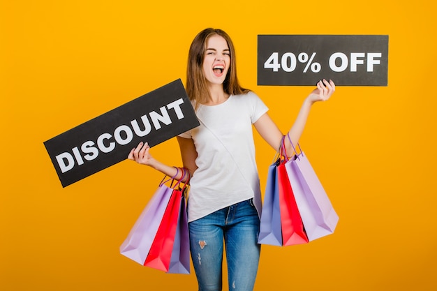 Beautiful brunette woman with colorful shopping bags and copyspace text discount 40% sign banner isolated over yellow