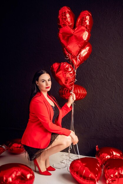 beautiful brunette woman with heartshaped balloons on a dark background valentines day