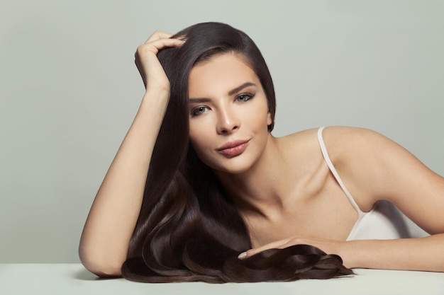 Beautiful brunette woman with long healthy shiny hair on white background