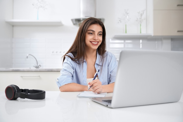 Bella donna castana che lavora nel computer portatile