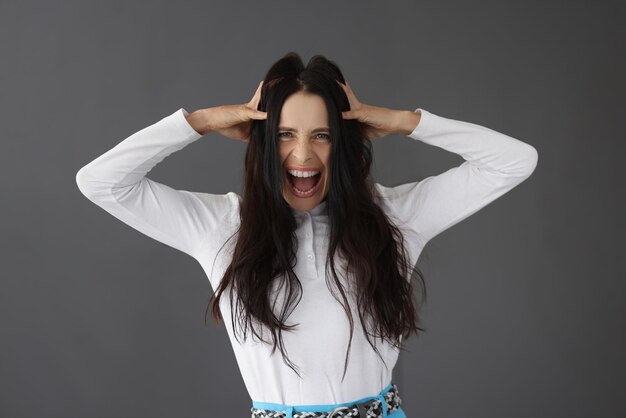 A beautiful brunette yells holding her head closeup concept stress negative emotions critical