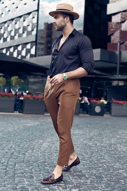 Beautiful brutal tanned muscular hipster man posing in the streets