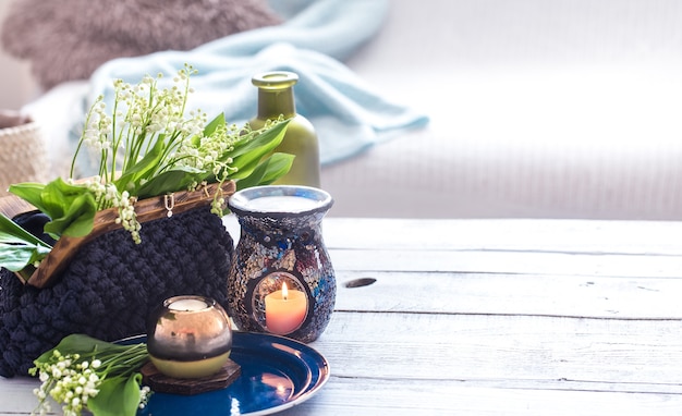 Beautiful burning candles with green leaves in purse on white table