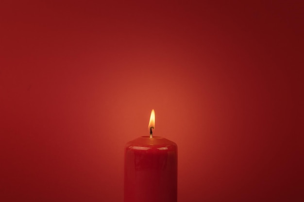 Beautiful burning red candle on a red background. The concept of a romantic relationship.