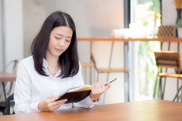 Beautiful business asian woman reading on notebook on table