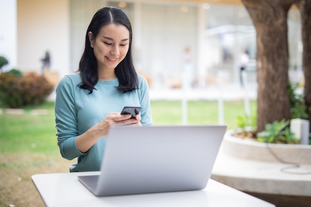 Beautiful Business Asian woman with suit working in office desk using computer with smart phone and