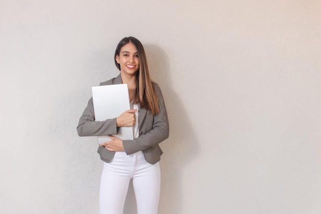Beautiful business girl holding laptop with her arms on white background