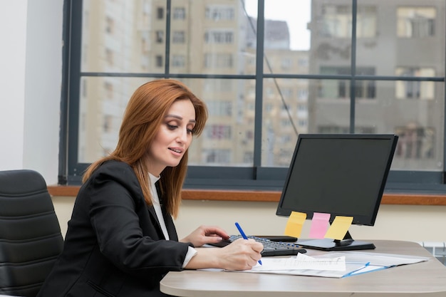 Beautiful business lady sitting at the desk and writing her notes