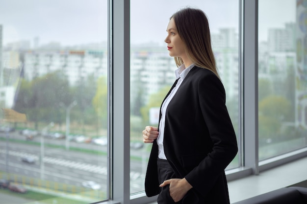 Beautiful business lady standing thoughtfully by the window