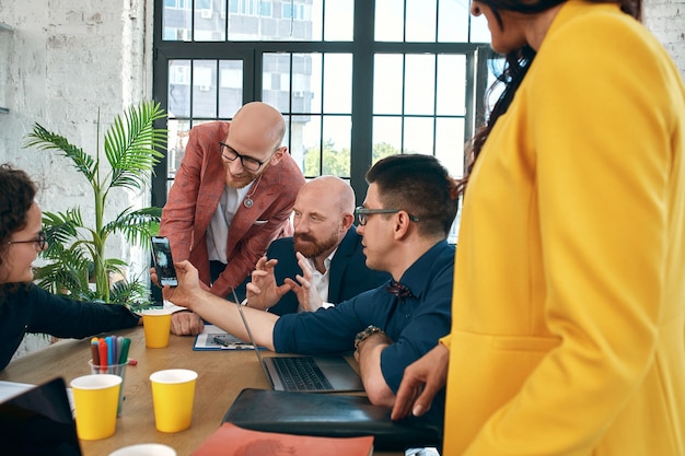 Photo beautiful business people are using gadgets, talking and smiling during the conference in office. selective focus