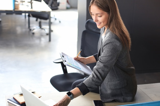 Beautiful business woman is examining documents while working in the office.