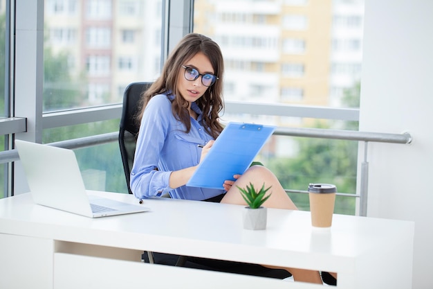 Beautiful business woman is using a laptop and smiling while working in office