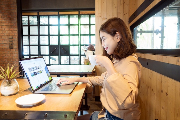 La bella donna di affari sta lavorando con il suo computer portatile in caffetteria