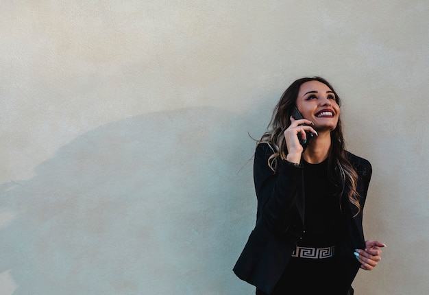 Foto bella donna d'affari all'aperto con il cellulare. giovane bruna al telefono