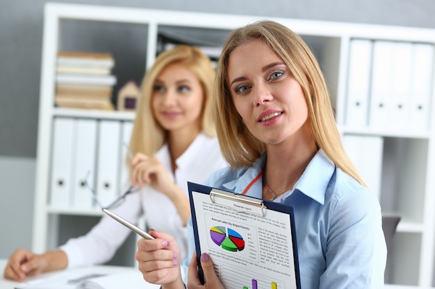 Beautiful business woman portrait. Holds a clipboard with financial statistics fashion style curly hair