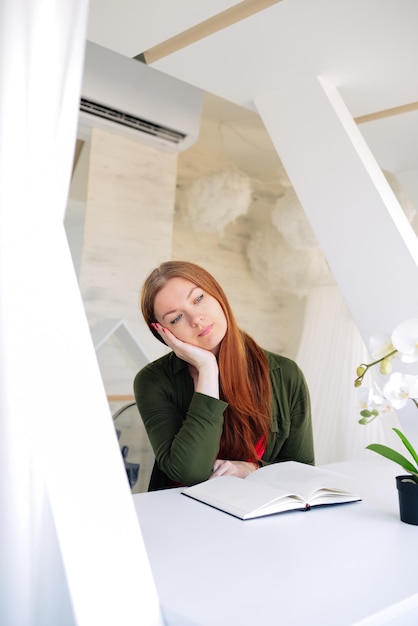 beautiful business woman sits in a cafe and reads a book.  hand supports the face.