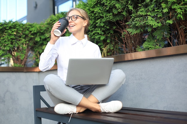 Beautiful business woman sitting near business center and using laptop.