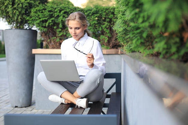 Foto bella donna di affari che si siede vicino al centro di affari e che per mezzo del computer portatile.