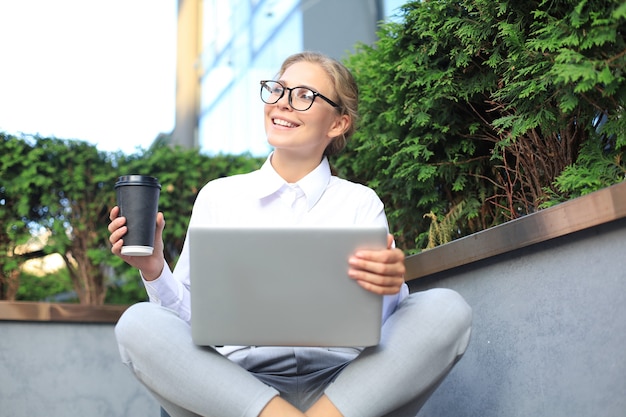 Beautiful business woman sitting near business center and using laptop.