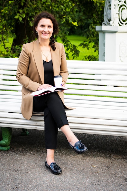 Beautiful business woman sitting in the park on a bench