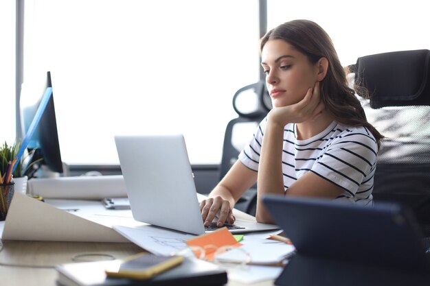 Beautiful business woman in smart casual wear working on laptop in the office.