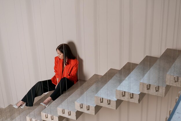 Photo beautiful business woman on stairs in red jacket is experiencing collapse
