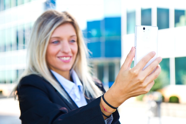 美しいビジネス女性は彼女の携帯電話でselfieを取ります