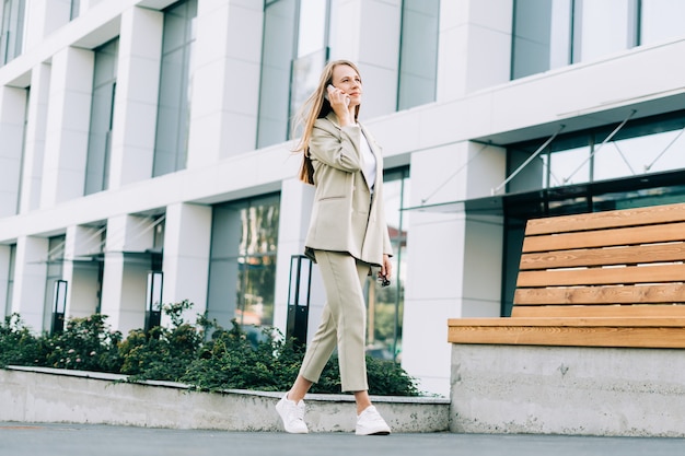 Beautiful business woman talking over the phone and walking in city street