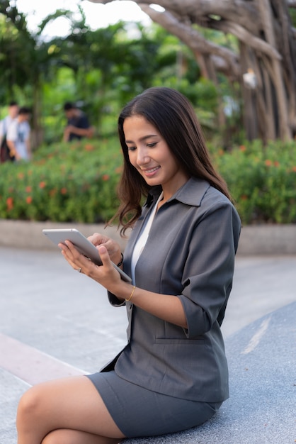 屋外作業のためのipadを使用して美しいビジネス女性