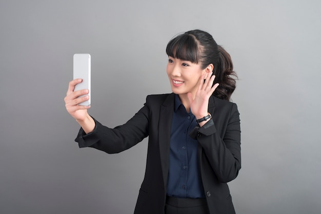 Красивая женщина бизнес с помощью смартфона на сером фоне