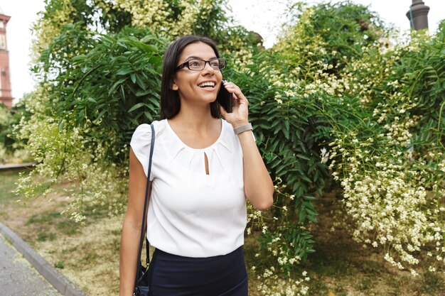 야외에서 휴대 전화로 이야기를 걸어 아름 다운 비즈니스 우먼