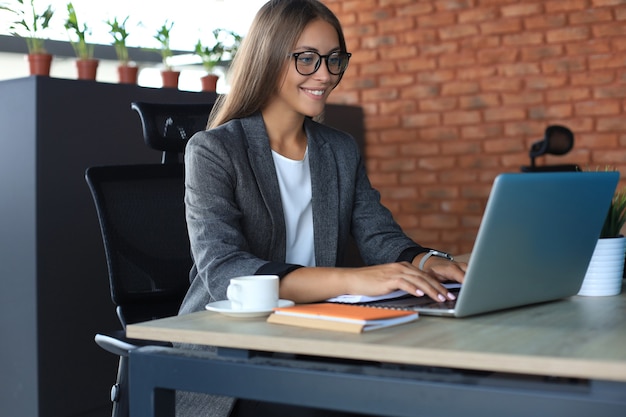 Bella donna d'affari che lavora al computer portatile in ufficio.