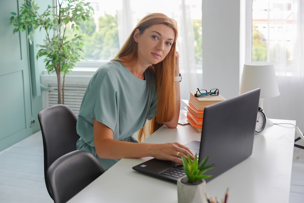 Bella donna d'affari lavora in ufficio su un laptop freelance al lavoro