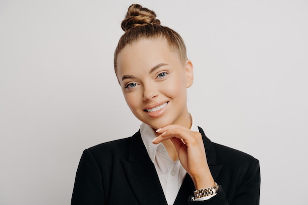 Beautiful businesswoman in formal attire confidently posing with a bun smiling hand on chin