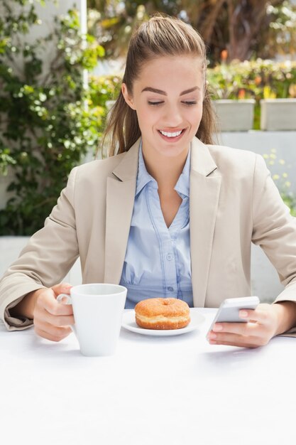 Beautiful businesswoman having a coffee and muffin