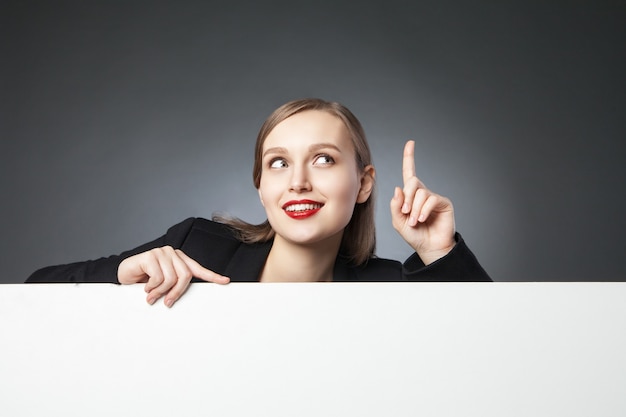 Beautiful businesswoman looking up with index finger up