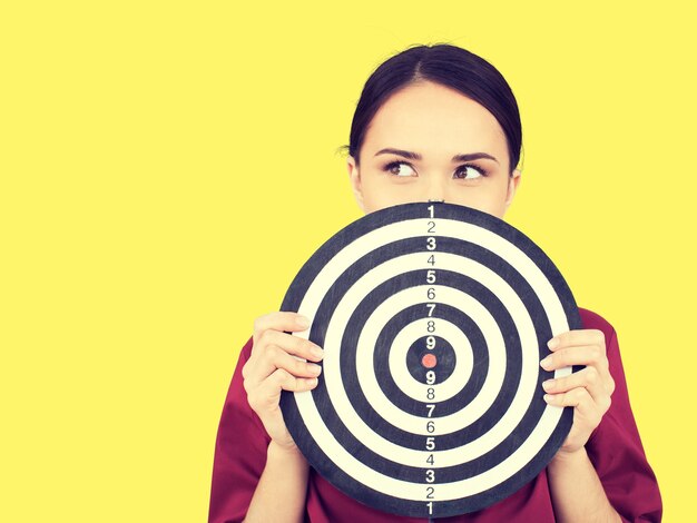 Beautiful businesswoman portrait holding round target of darts, isolated.