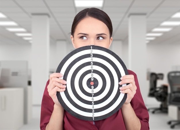 Beautiful businesswoman portrait holding round target of darts